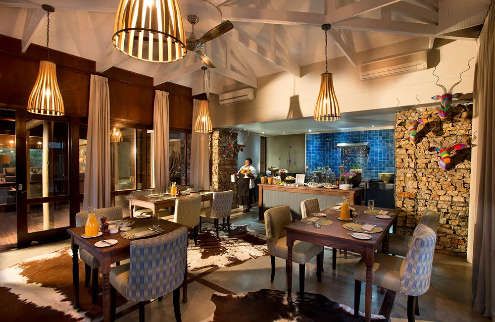 Open interactive kitchen with hanging pendant lights and a blue-tiled feature wall