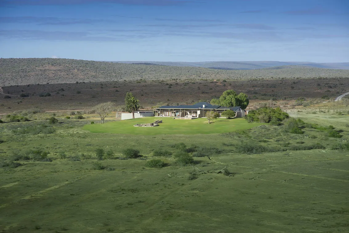 Aerial of Fort House standing alone on the Kwandwe plain with mountains in the distance