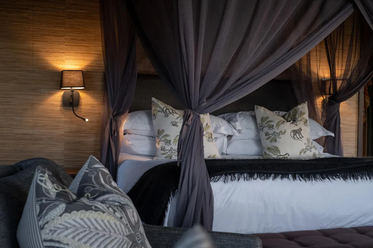Detail of the four-poster bed with mosquito net and printed scatter cushions