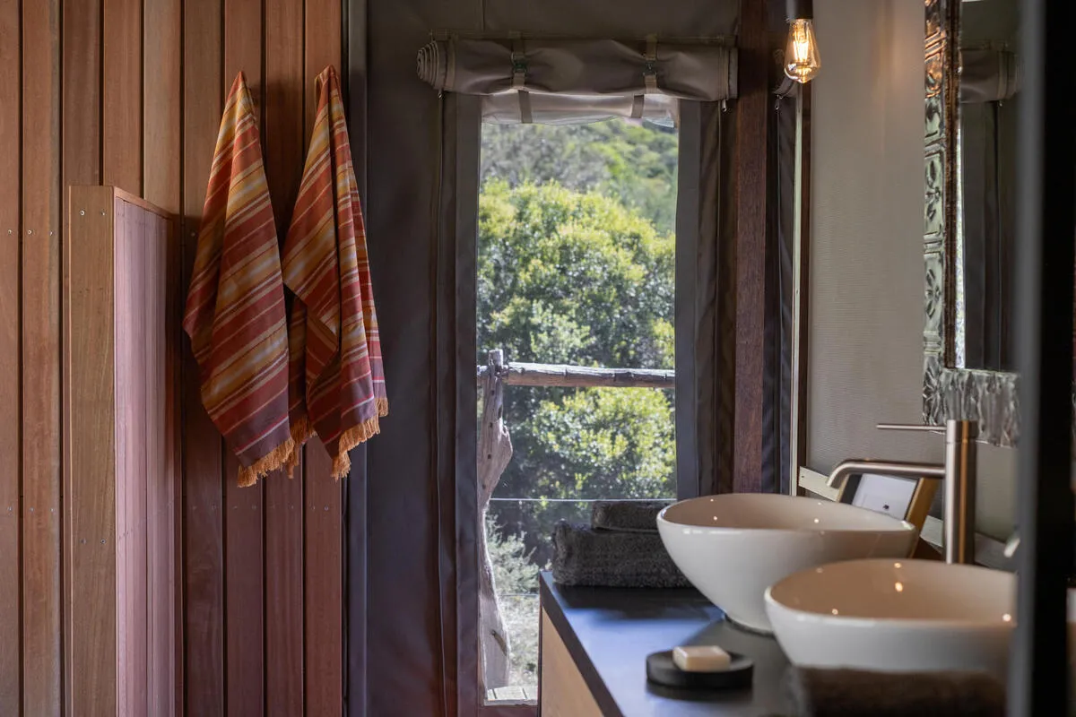 Tent bathroom detail with twin basins and a window onto the bush