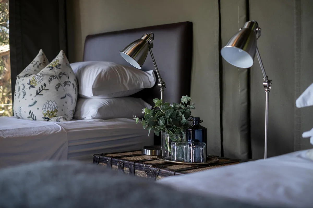Bedside detail with dual reading lamps and vintage trunk side table