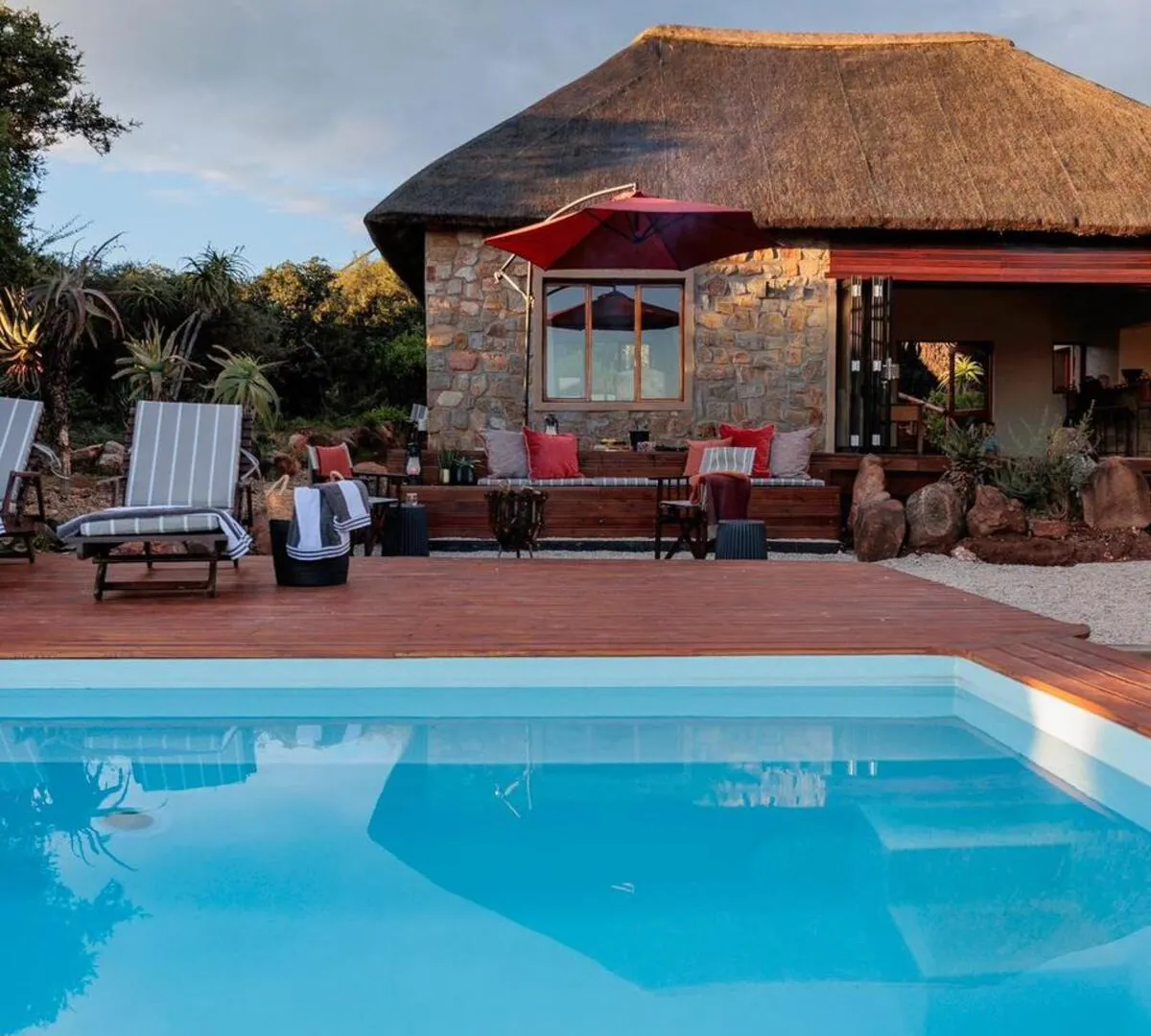 Stone-and-thatch suite exterior at sunset with private pool and outdoor lounge