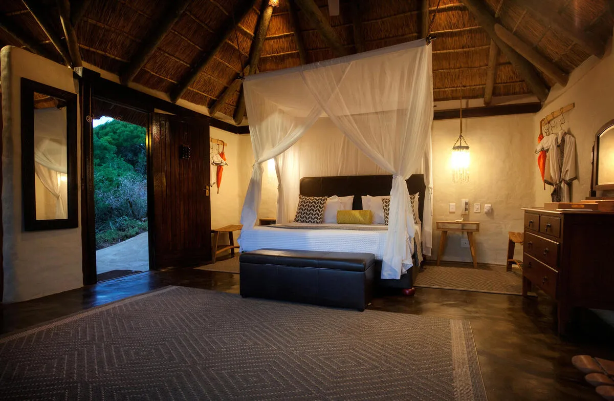 Four-poster bedroom with sliding doors opening to the bushveld