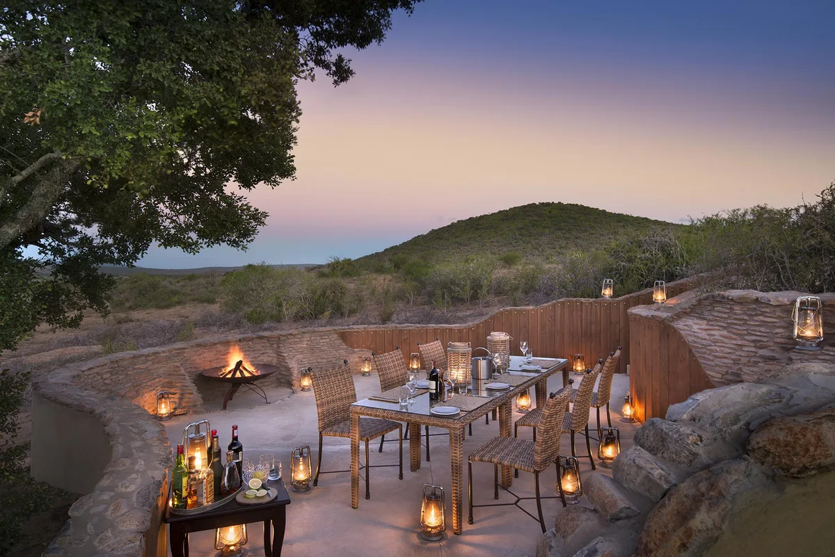 Outdoor boma with sundowner table and lanterns at dusk