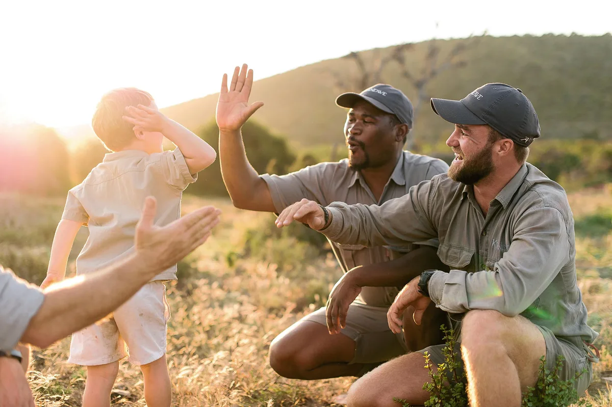 A guest high-fives the rangers after an Eco-Warriors conservation activity at sunset